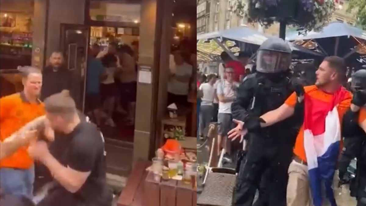 Two men fighting outside a bar. Police officers intervening to restrain one man wearing a flag. Onlookers in the background