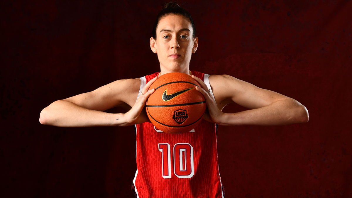 A basketball player wearing a jersey with the number 10 poses with a basketball in front of their chest