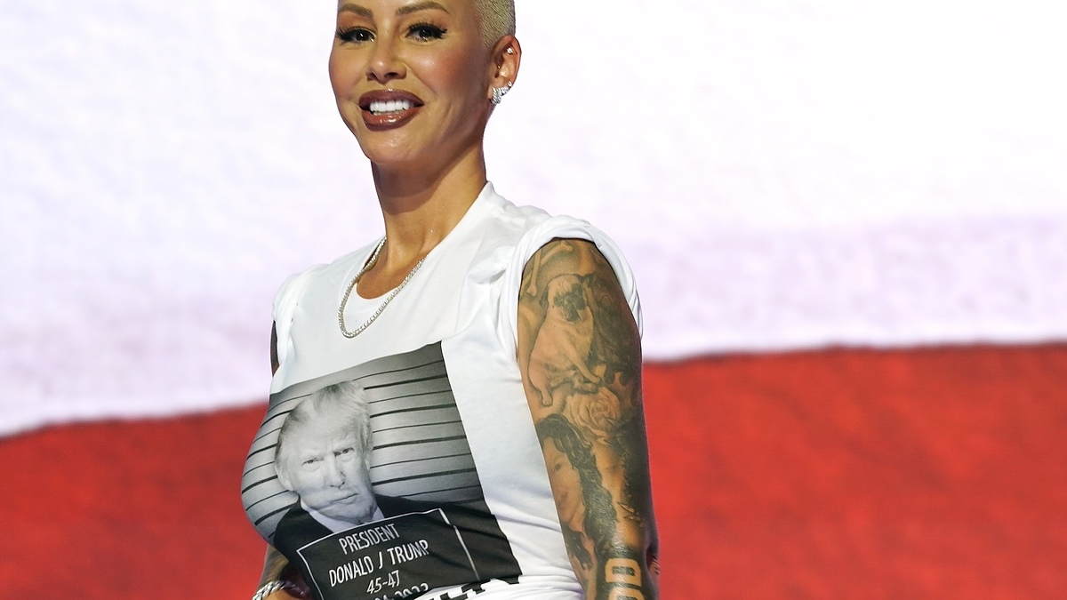 Amber Rose wearing a sleeveless shirt featuring a mugshot of Donald Trump with text "President Donald J. Trump 45-47." She has tattoos on her arms and a necklace