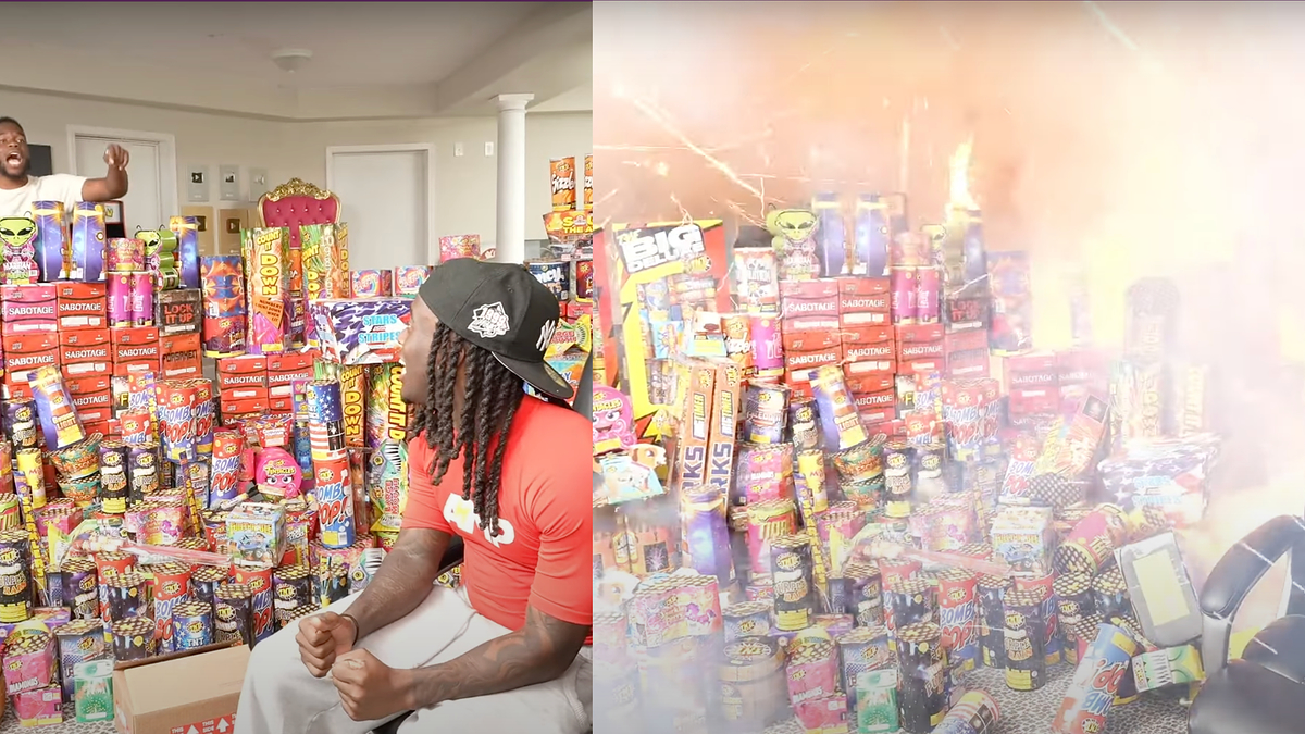 Several people are in a room filled with fireworks, with one man setting them off, causing an explosion of light and smoke. Only the back of one person is visible