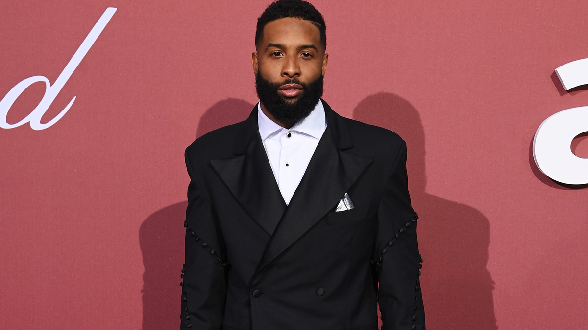 Odell Beckham Jr. on the red carpet at the amfAR event, wearing a black tuxedo with a white dress shirt and black bow tie