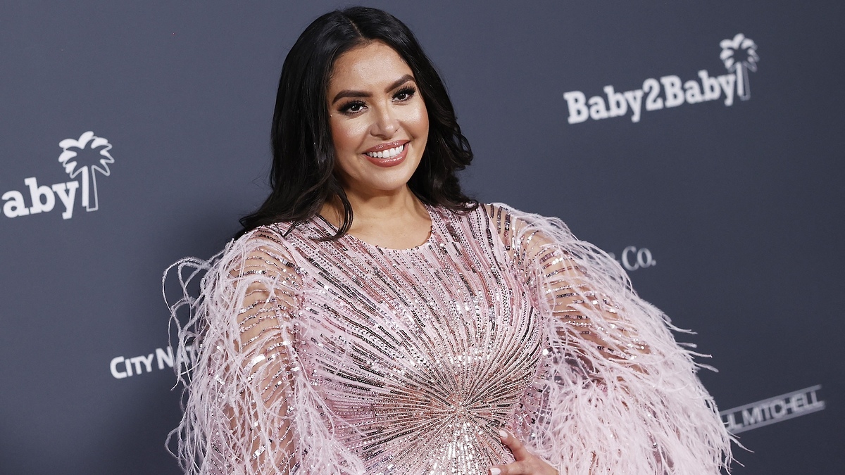 Woman in a sparkling, feathered dress posing on the red carpet at the Baby2Baby event