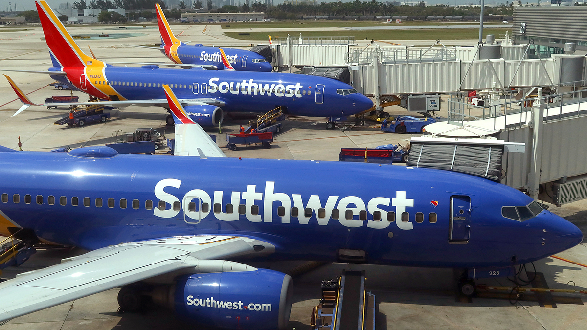 Southwest Airlines planes are parked at the gate of an airport terminal, with the airline's logo visible on the aircraft bodies
