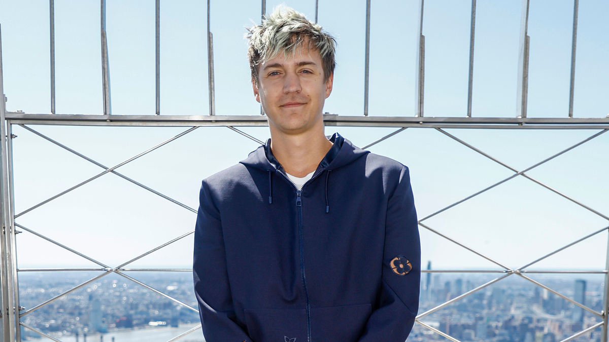Tyler "Ninja" Blevins poses in a casual hoodie in front of a cityscape atop a tall building