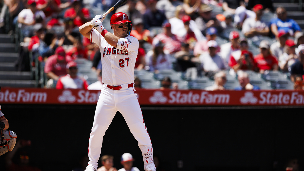 A baseball player from the Angels, wearing a uniform with the number 27, prepares to bat during a game. The crowd is visible in the background