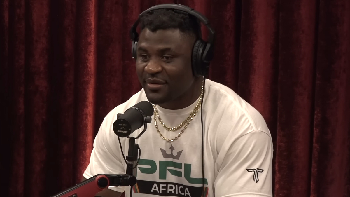 Francis Ngannou speaking into a microphone during a podcast interview, wearing a PFL Africa shirt and headphones
