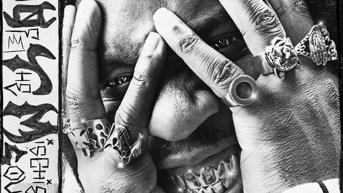 Burna Boy covers his face with his hands adorned with multiple rings in an intense close-up image. Text on the left appears to be artistic and stylized