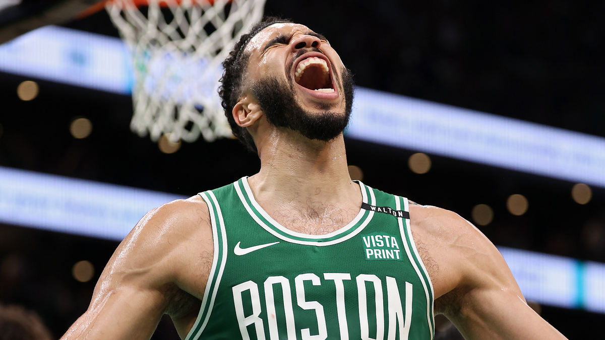 Jayson Tatum, wearing a Boston Celtics basketball jersey, passionately shouts during an intense moment in a game