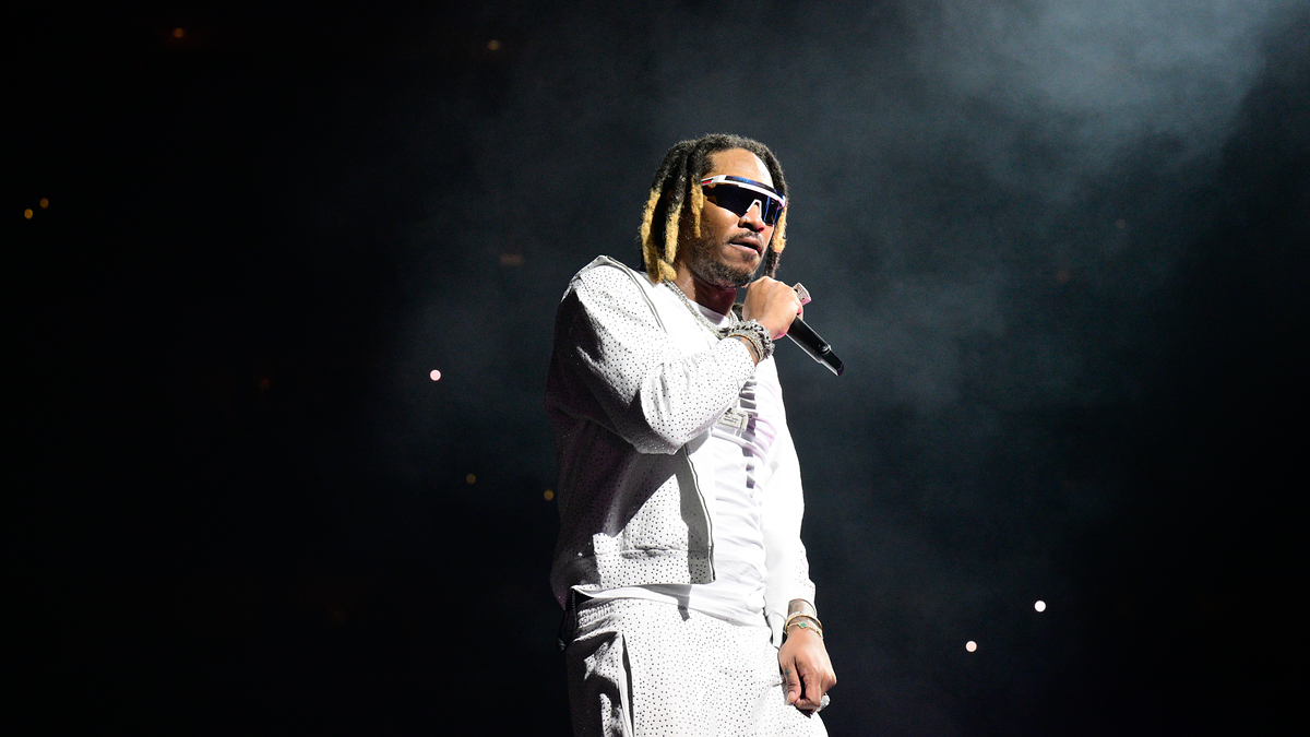 Future performing on stage, wearing a stylish white outfit with sunglasses, holding a microphone