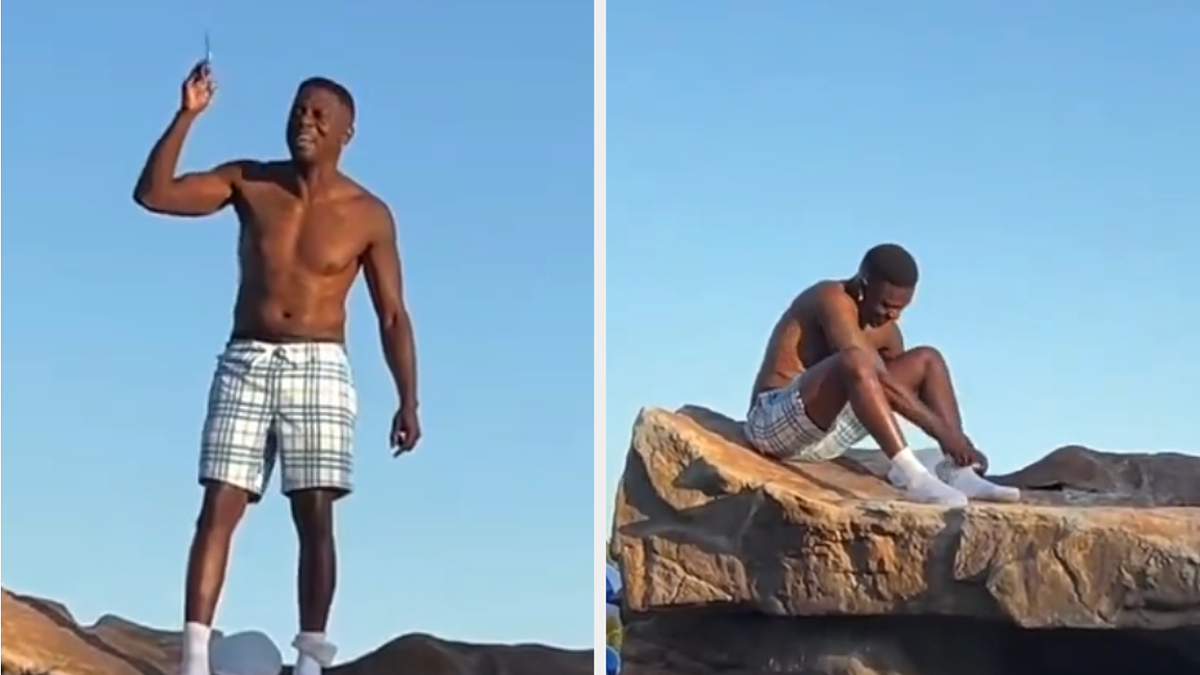 Musician Boozie on a large rock, shirtless and in checkered shorts, holding an object in the air in one frame and sitting down in the second frame