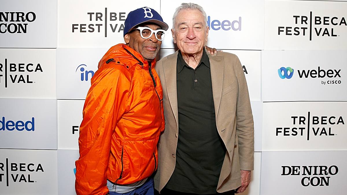 Spike Lee in casual wear and baseball cap with Robert De Niro in a beige jacket posing together at the Tribeca Festival step-and-repeat backdrop