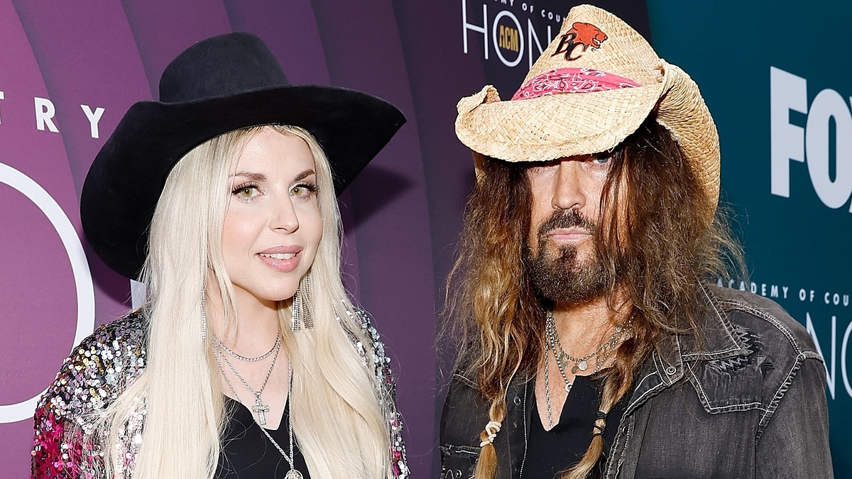 Billy Ray Cyrus and Firerose at the Country Music Awards, standing side by side. Both are wearing cowboy hats and stylish attire