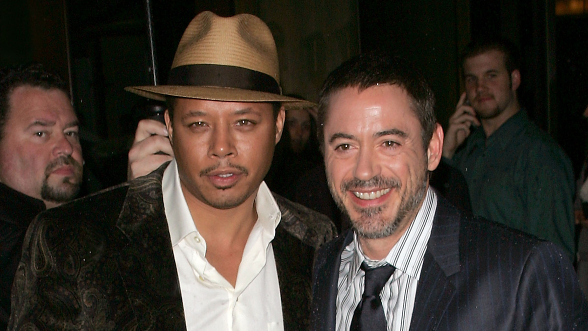 Terrence Howard in a fedora and Robert Downey Jr. in a suit and tie, standing together at a public event