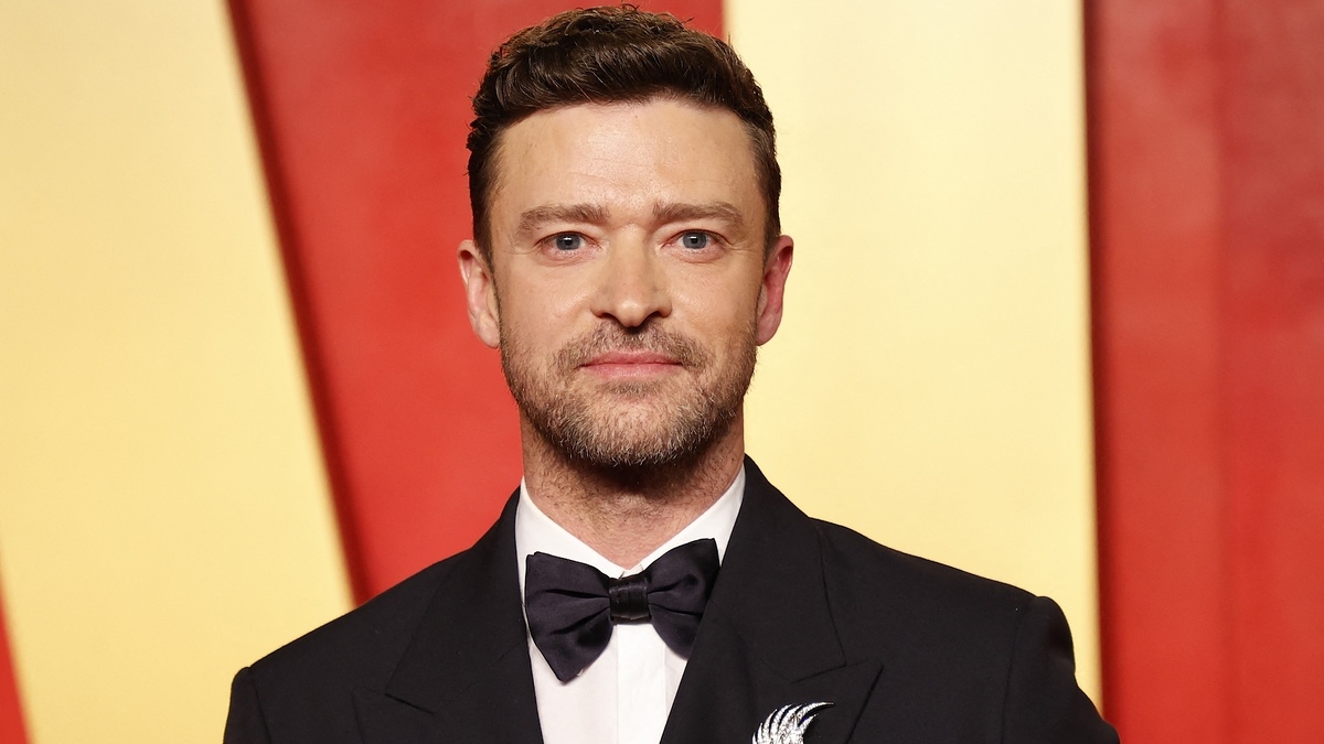 Justin Timberlake poses in a tuxedo with a bow tie on a red carpet