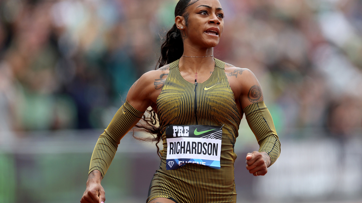 Sha'Carri Richardson sprinting during a track race, wearing a form-fitting athletic outfit with arm sleeves