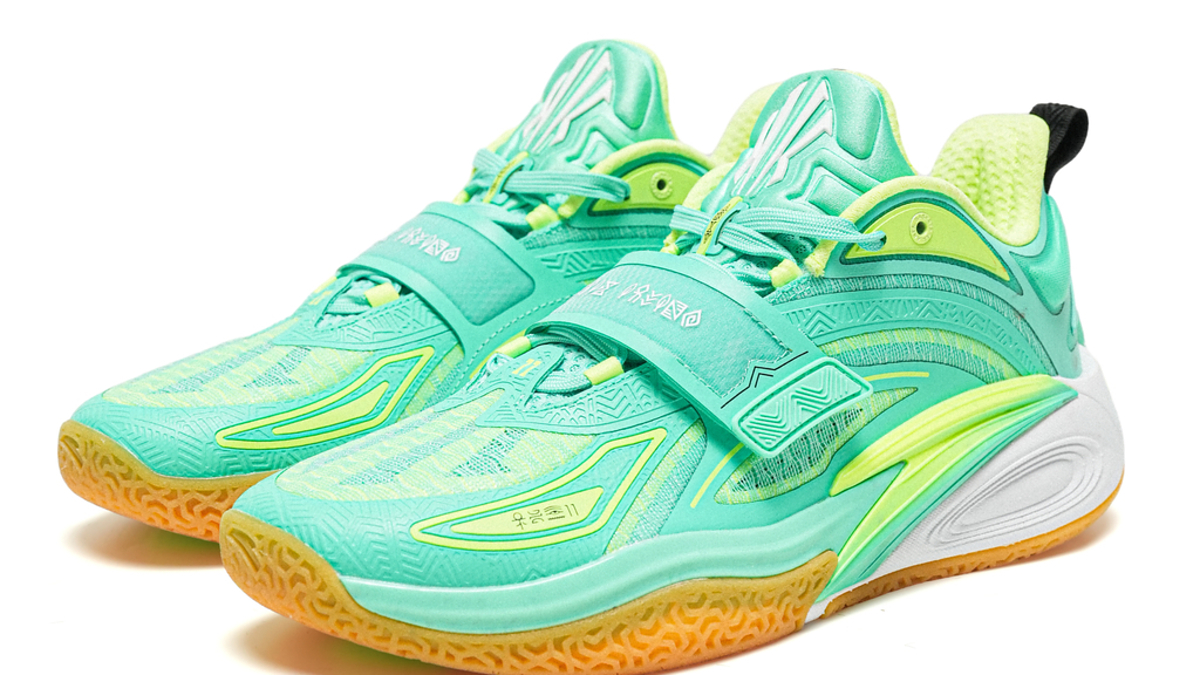 Pair of athletic sneakers with a modern design and textured soles. The shoes have a strap across the laces and feature various design details