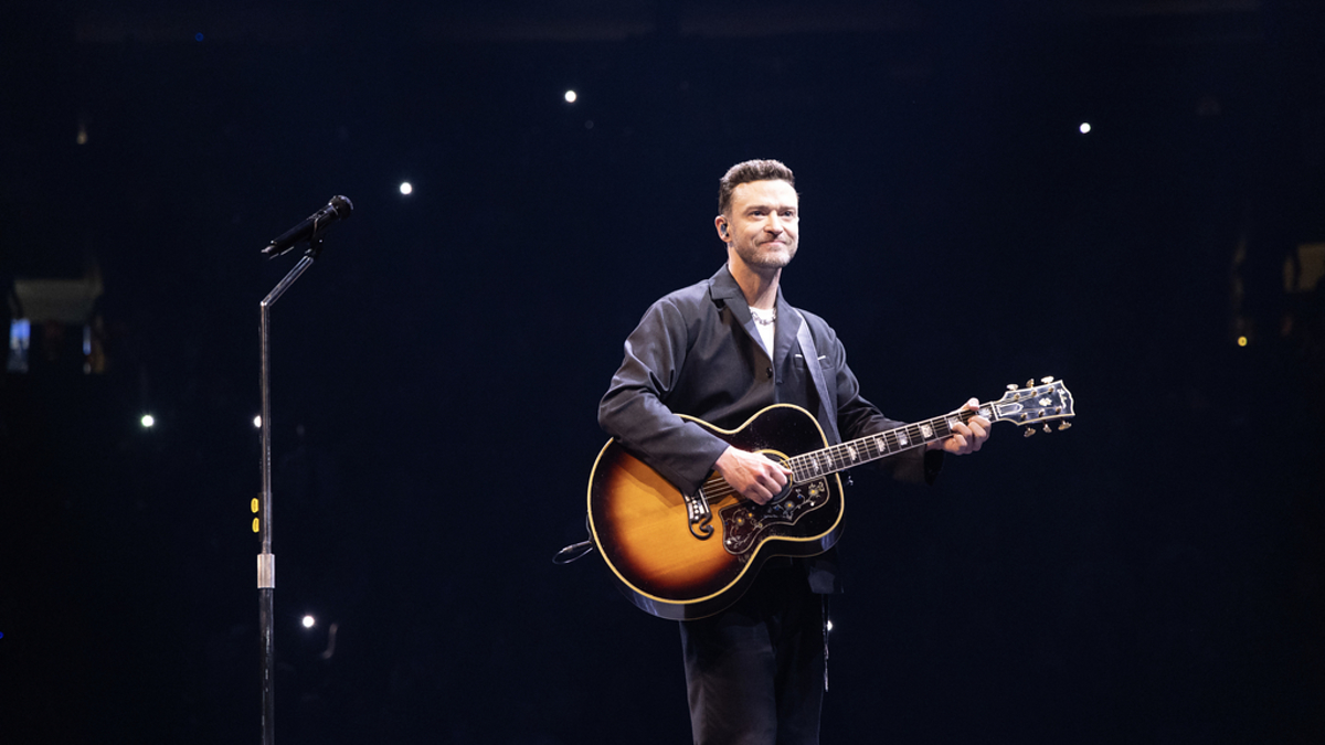 Man playing an acoustic guitar on stage during a performance