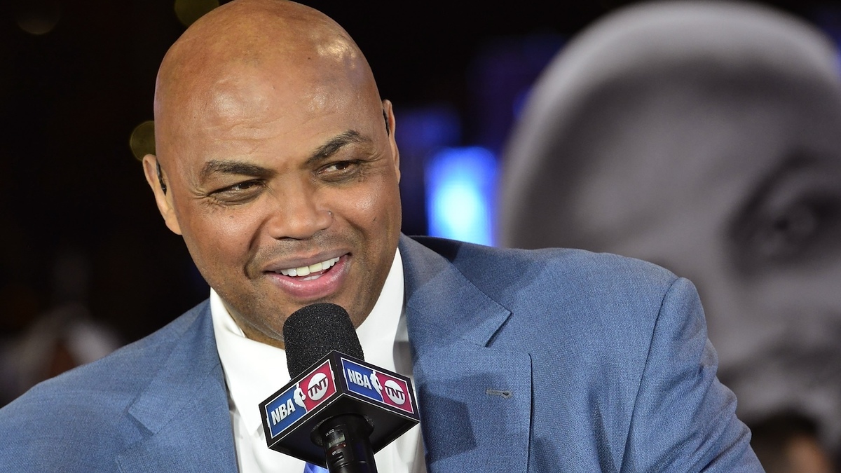 Charles Barkley in a blue suit speaks into an NBA on TNT microphone at an event