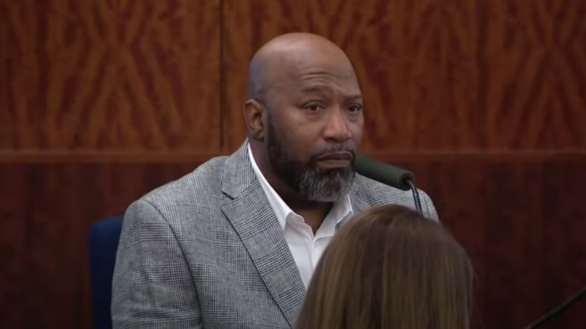 Bun B testifies at a public hearing, wearing a checkered suit jacket. He is known for being a rapper and a member of the rap duo UGK