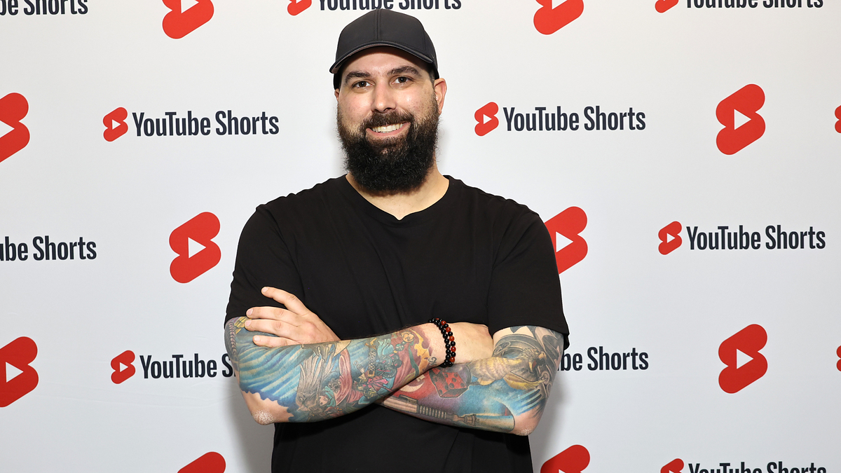 Person smiling in front of a backdrop with YouTube Shorts logos
