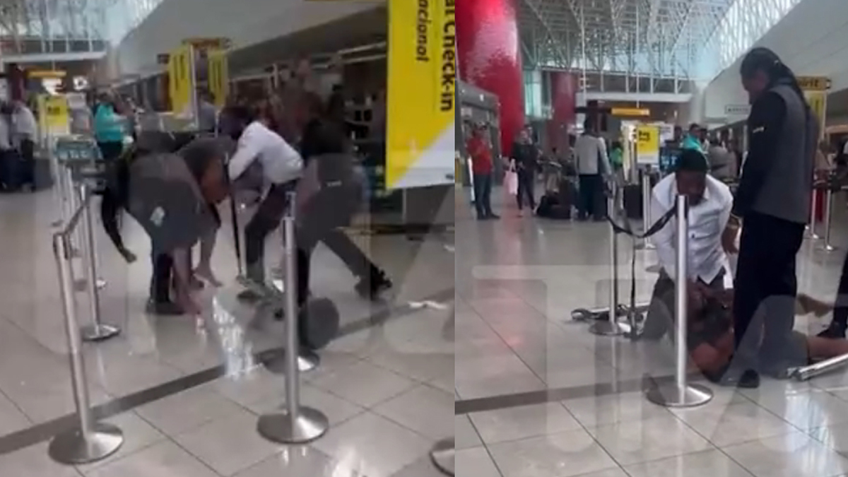 Airport security staff assist a person on the ground near Spirit Airlines counters in a crowded terminal
