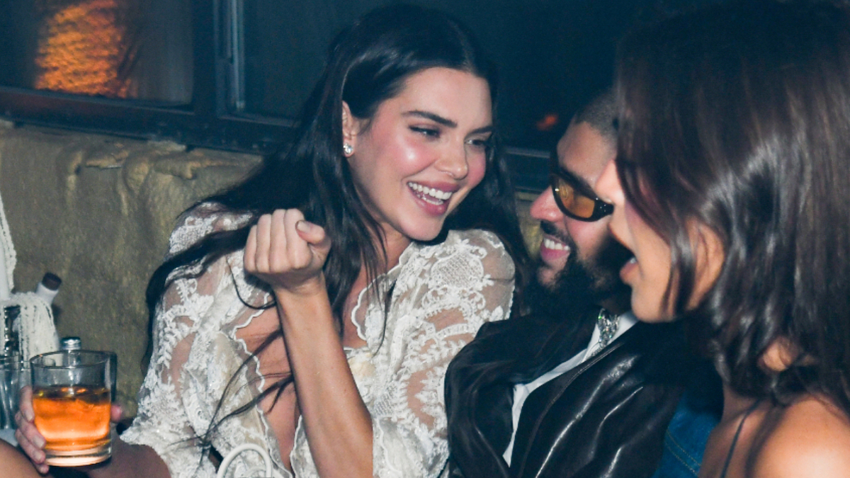 Two people laughing, one in lace attire and the other in a leather jacket, at a music event