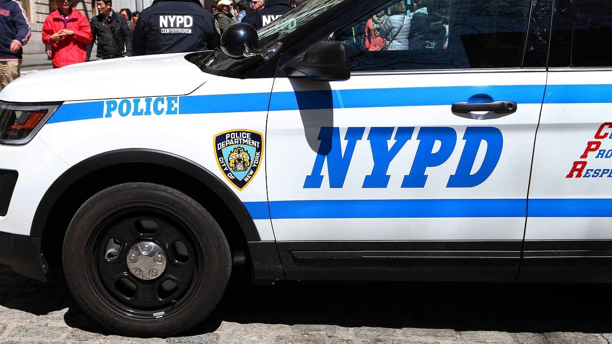 A New York Police Department (NYPD) vehicle parked with several people standing nearby