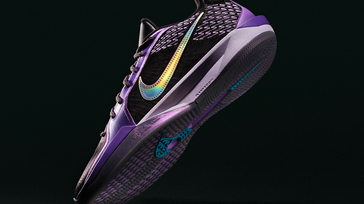 A sneaker features a colorful Nike swoosh on its side, with intricate designs around it. The sole has distinct patterns, highlighting the shoe's athletic design