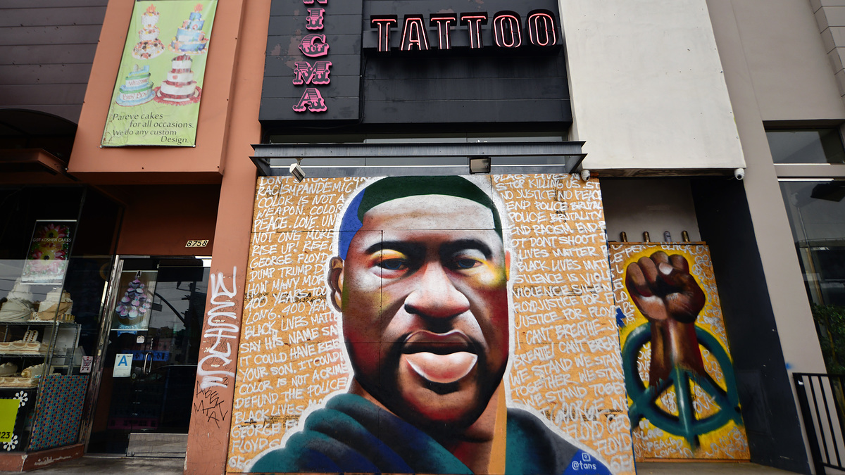 Mural of George Floyd with a raised fist symbol and a peace sign alongside text describing social justice messages