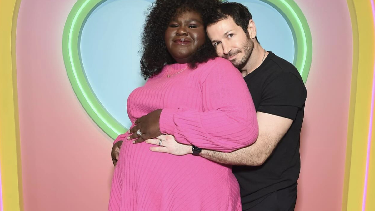 Gabourey Sidibe and Brandon Frankel on a Babylist backdrop; Gabourey in a chic pink dress, Brandon in a casual black outfit