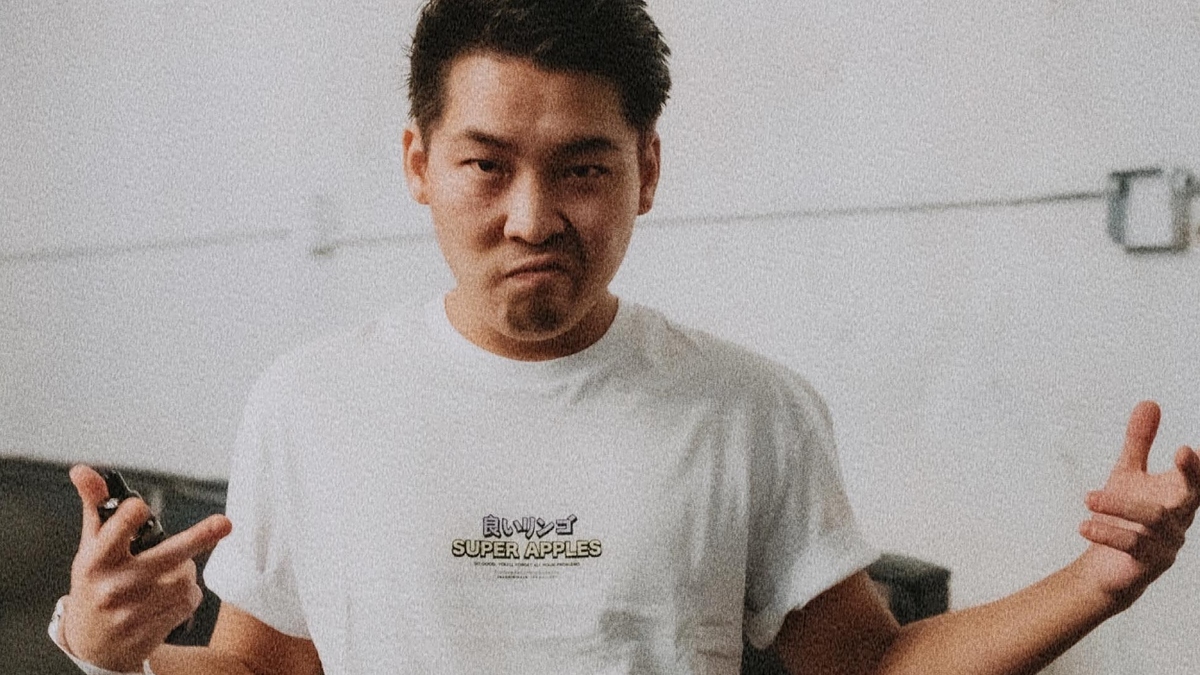 Person gesturing with hands, wearing a T-shirt with text, standing indoors