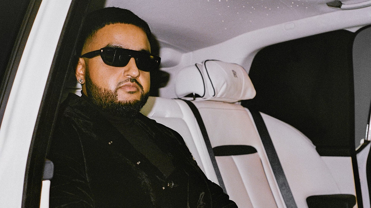 Music artist in a car, wearing sunglasses and a black jacket with textures