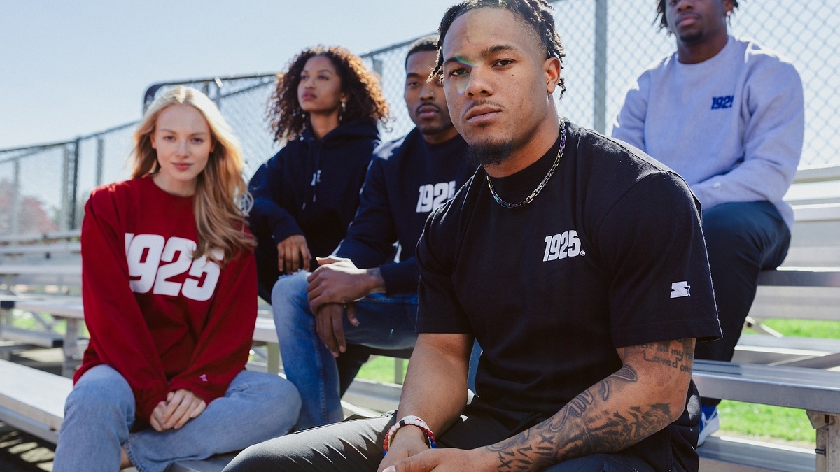 Five individuals sitting on bleachers, wearing casual sports-inspired clothing with numbers and logos
