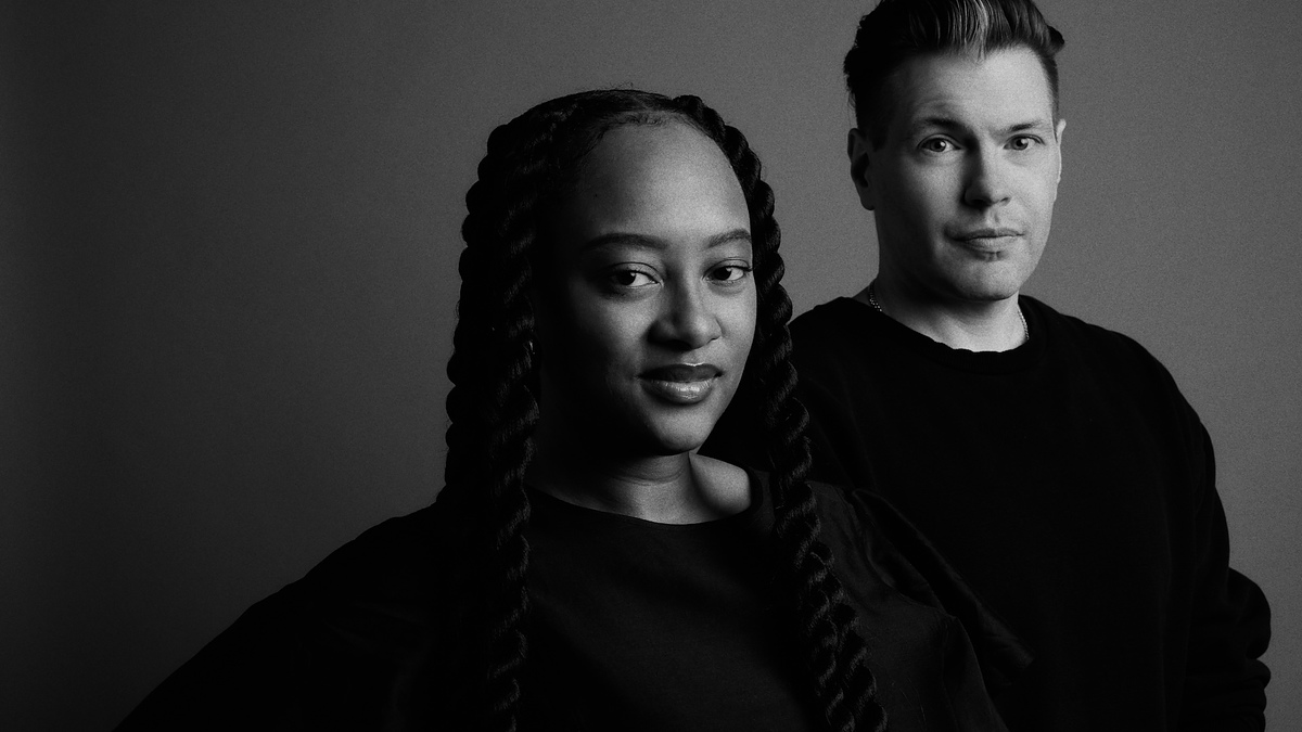 Two people posing for a photo, one with braided hair and the other with short hair