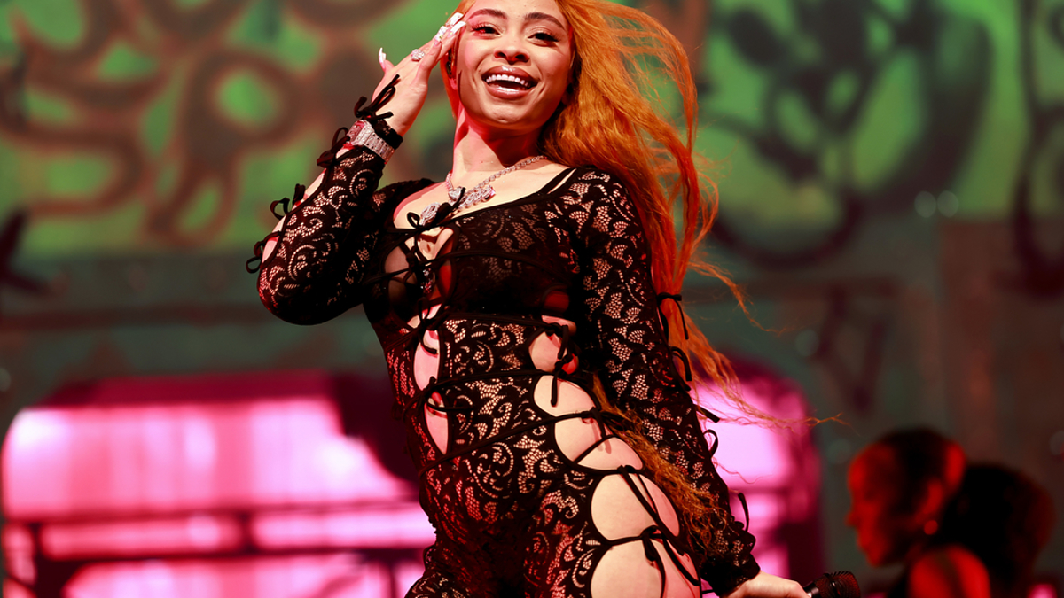 Person singing on stage in lace outfit with backdrop lighting and patterns