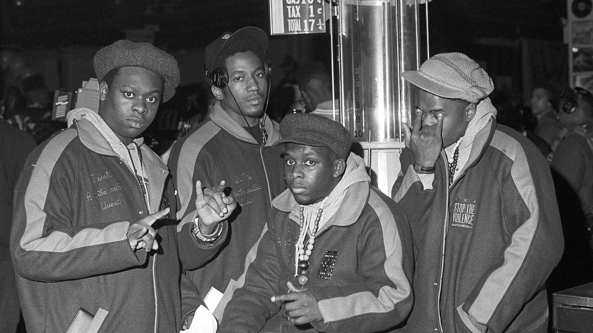 Four individuals posing together, two are making hand gestures. They wear matching jackets with "Security" written on them
