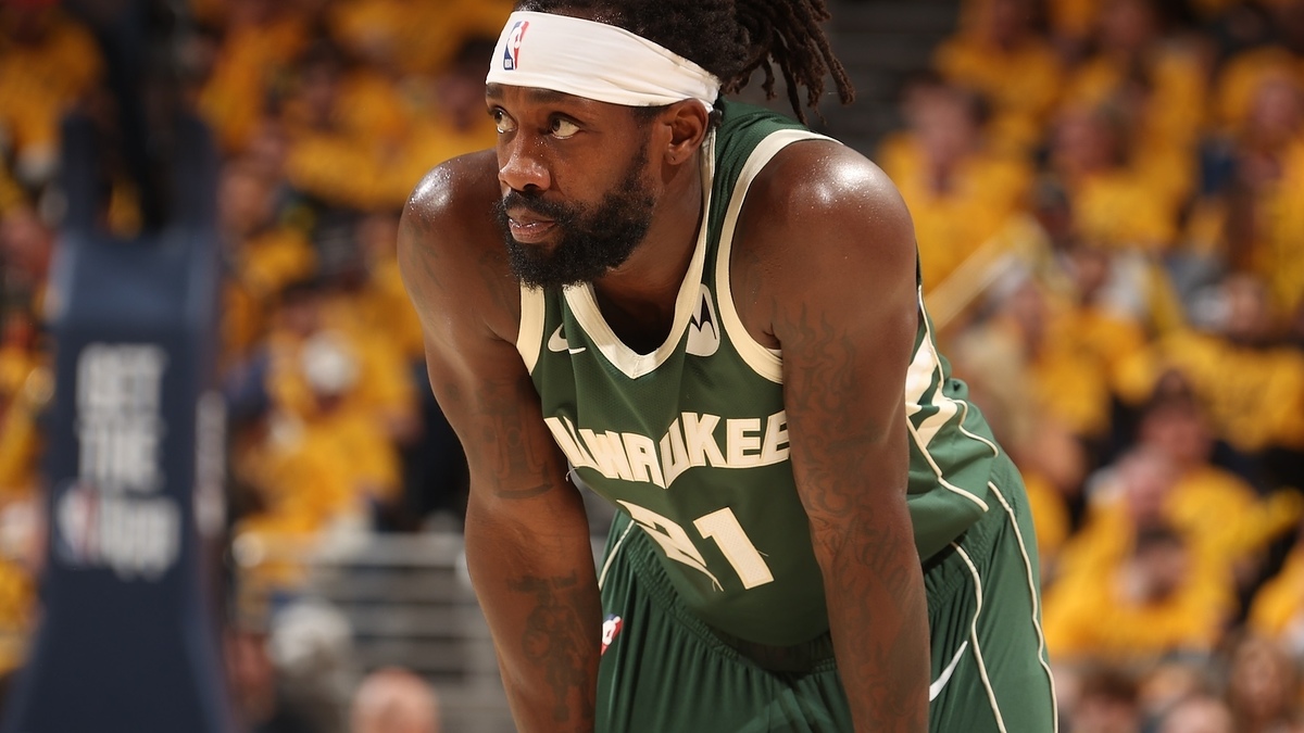 Basketball player in green uniform with 'Milwaukee' emblazoned, leaning forward resting on his knees during a game