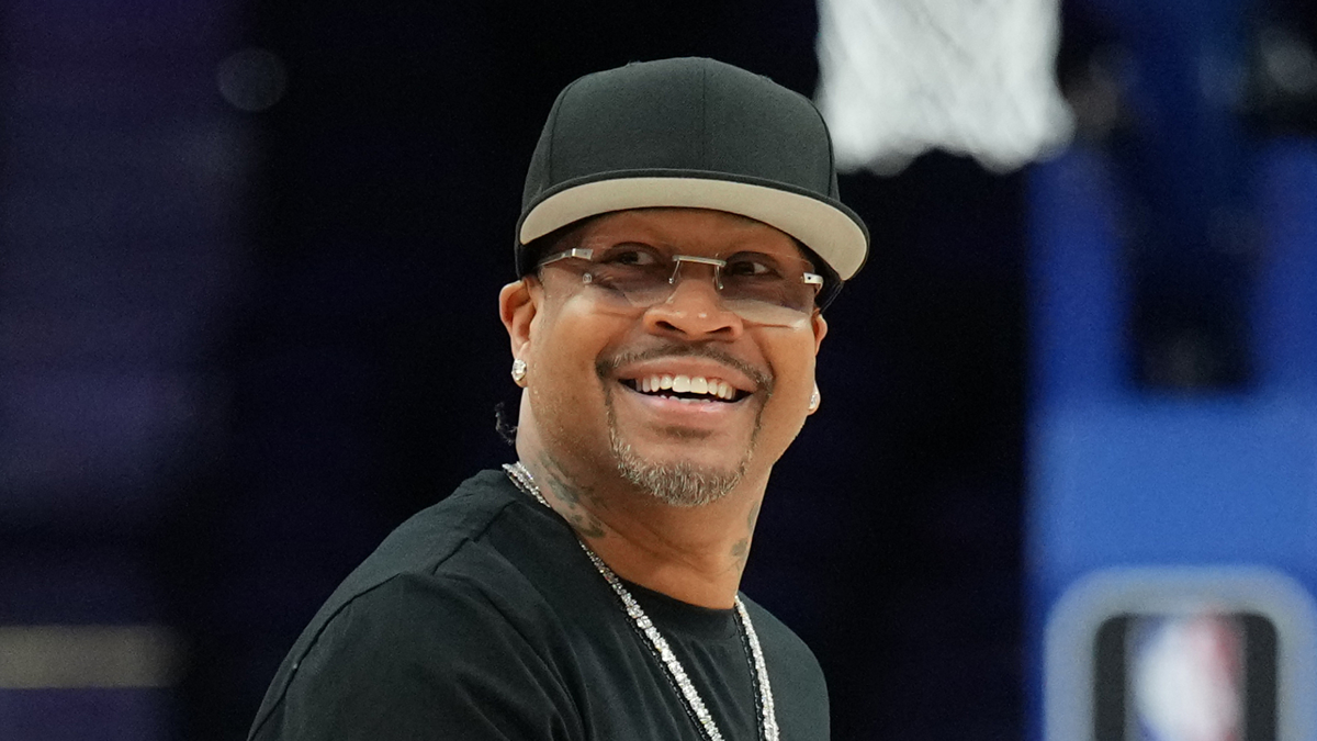 Man smiling wearing black hat, shirt, and sunglasses