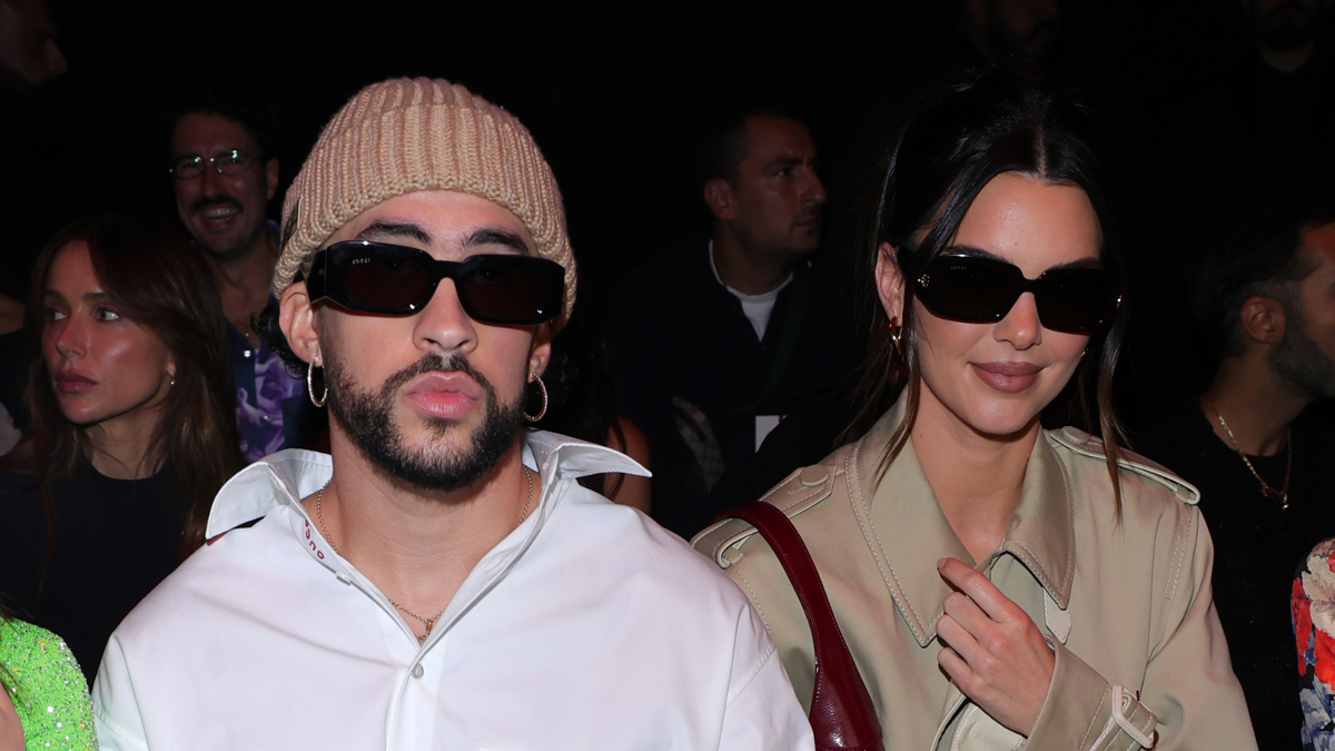 Bad Bunny and Kendall Jenner sit in the front row at a fashion event wearing dark sunglasses and fashionable outfits