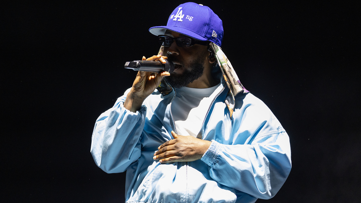 Rapper in a blue jacket and cap performing with a microphone