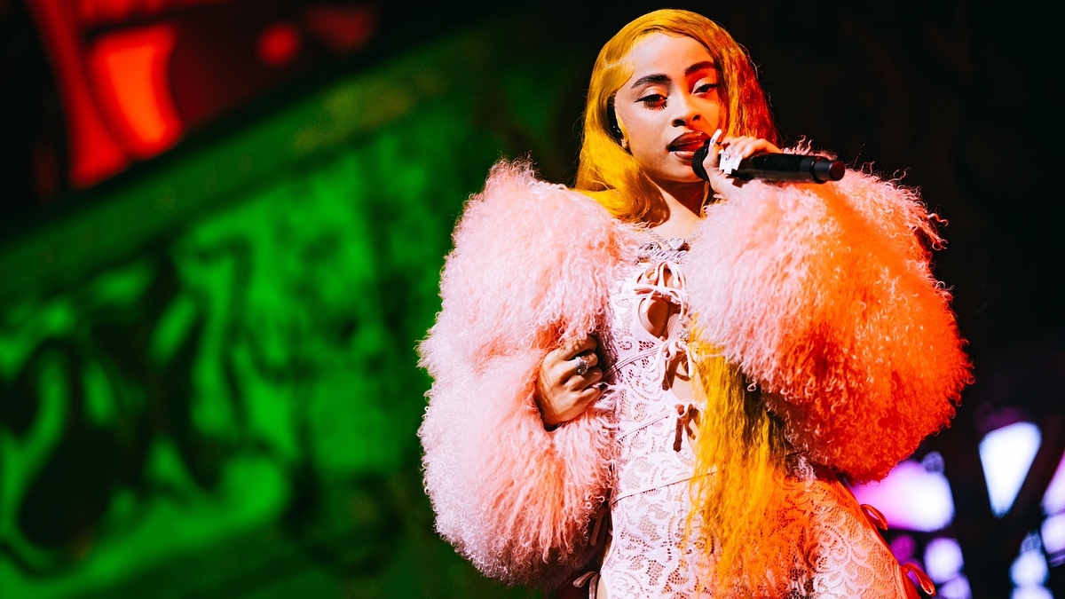 Person singing on stage wearing a fluffy jacket and lace outfit