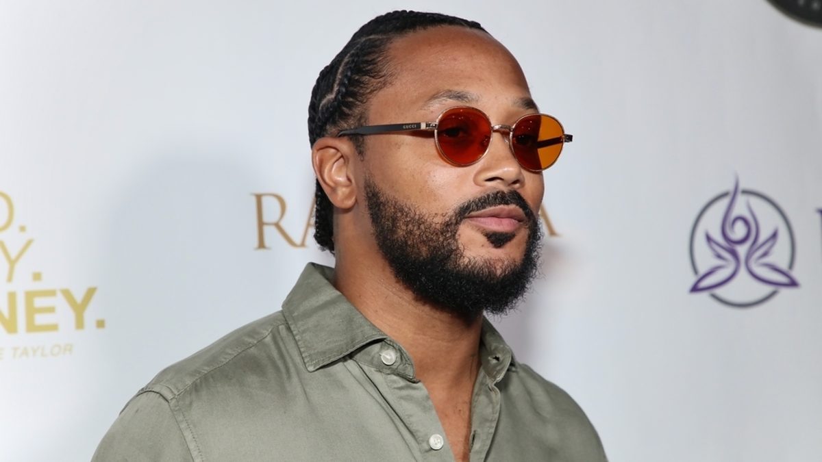 Man with braided hair and round sunglasses at an event