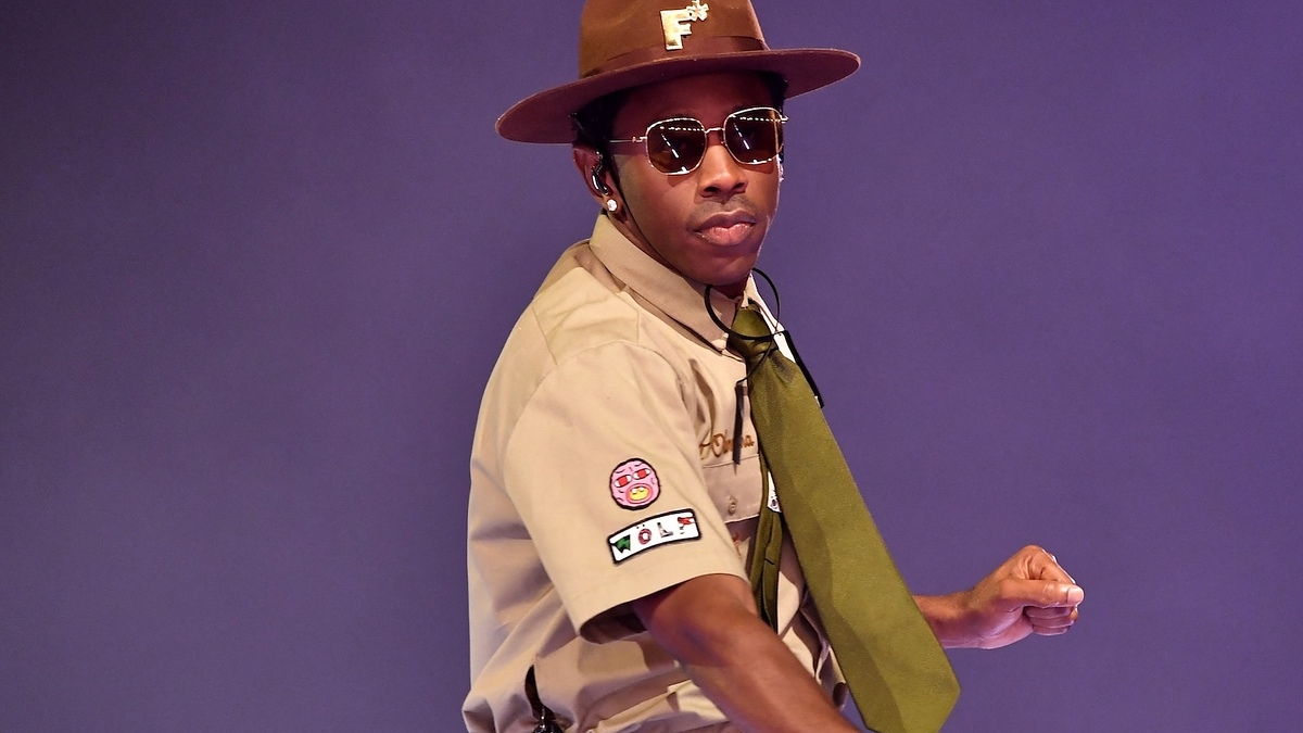 Person in scout-inspired outfit with hat, neckerchief, and badges; striking a pose