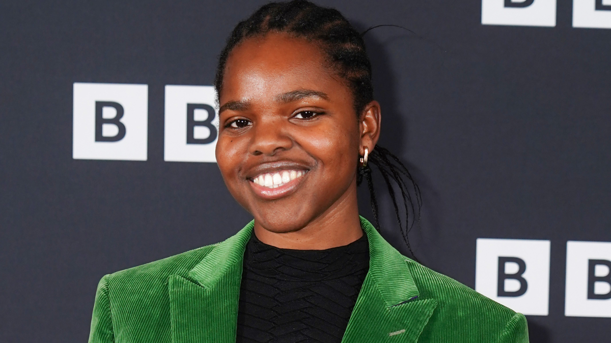 Woman in a green blazer and black top smiles at a BBC event
