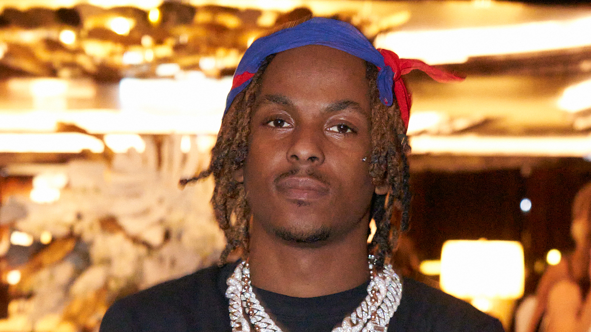 Man with dreadlocks and headscarf, wearing a necklace, looking at the camera