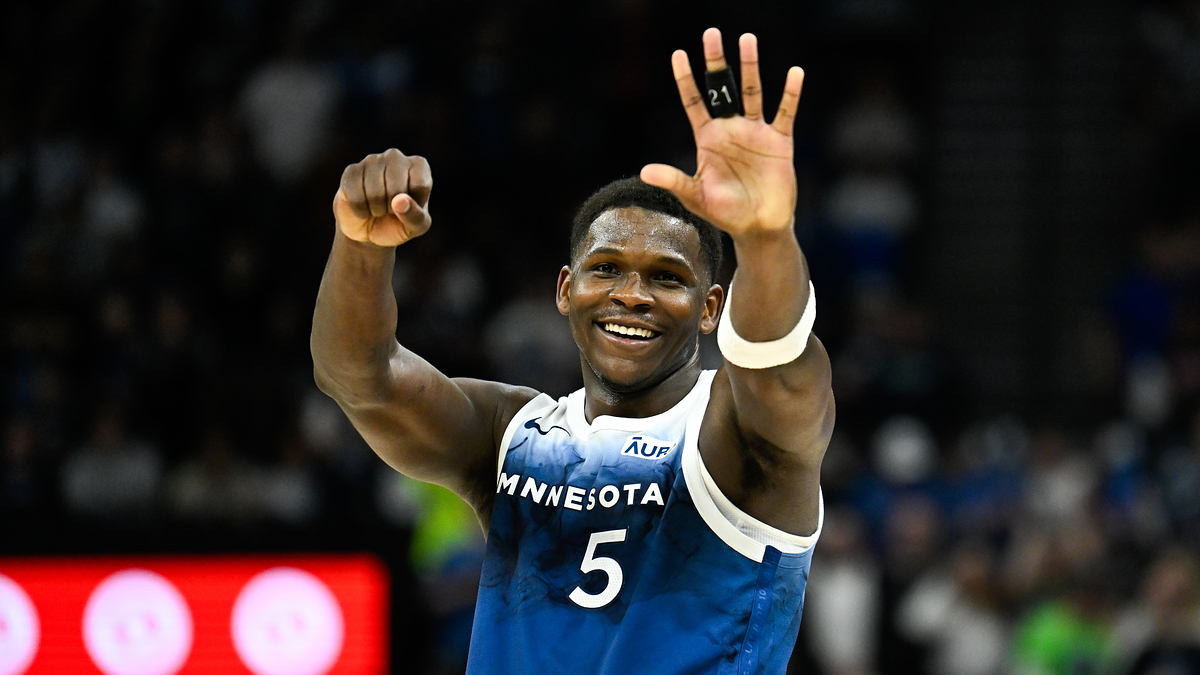 Basketball player in blue jersey number 5 raises a smiling double thumbs-up on the court