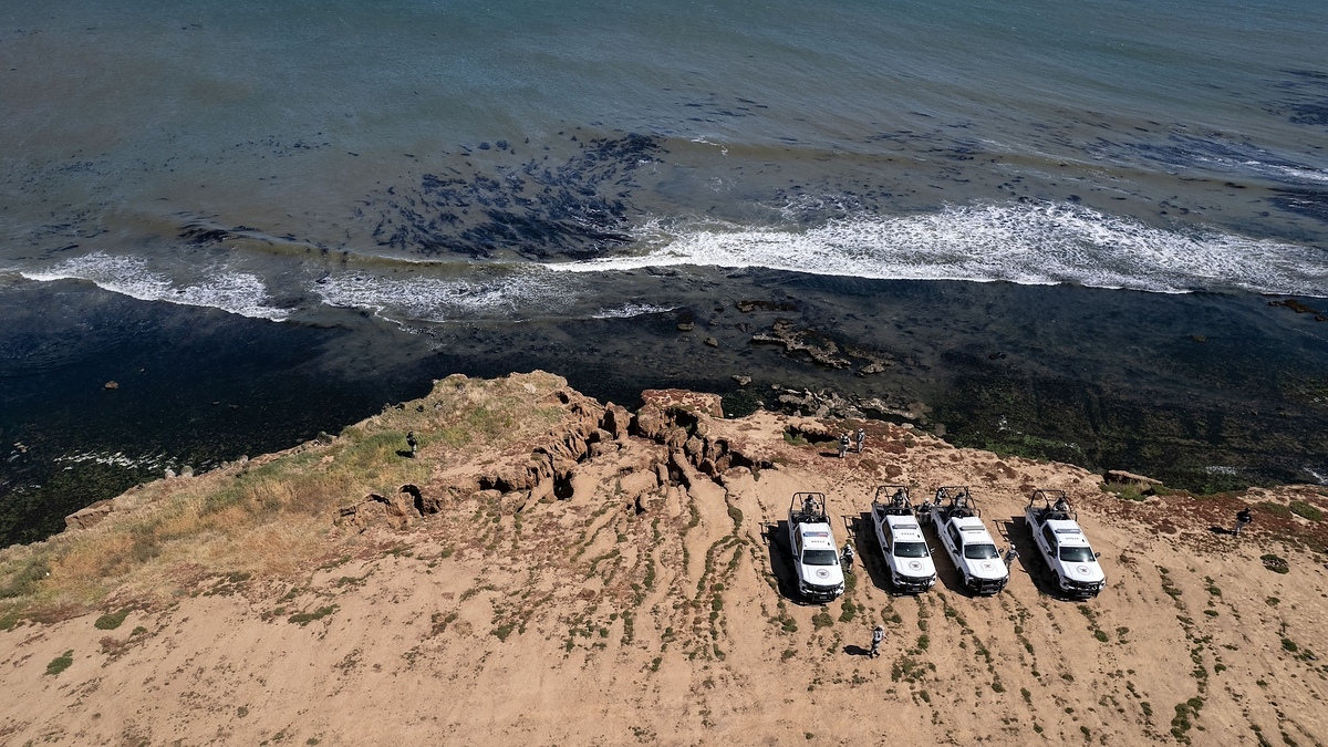 Aerial view of five boats near a coastline with waves and sandy terrain