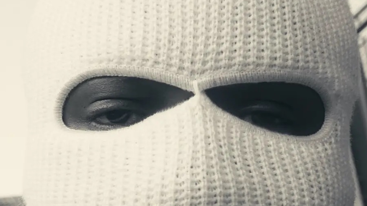 Close-up of a person wearing a knitted mask with eye and mouth openings