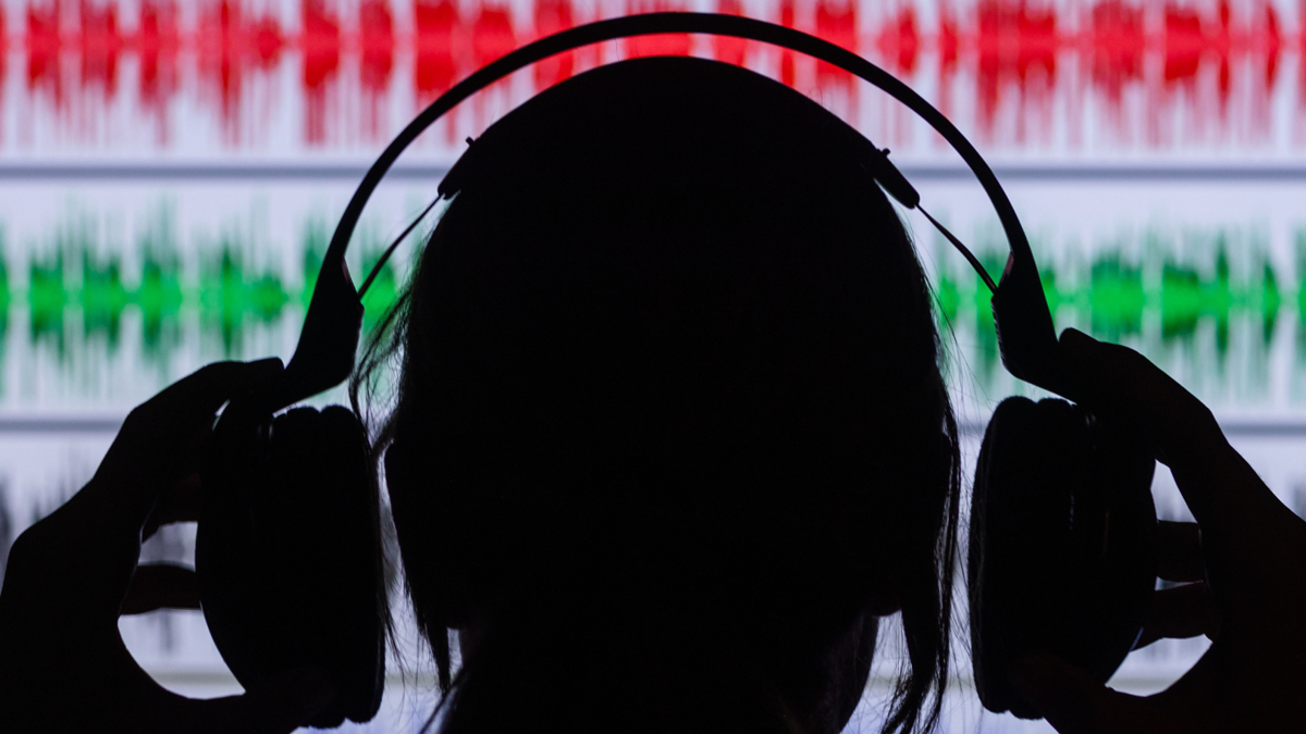 Silhouette of a person with headphones against a background of audio waveform graphics