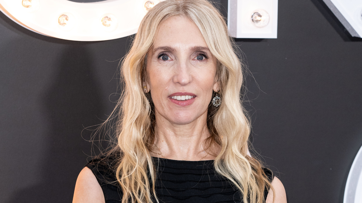 Woman in a sleeveless black dress smiling for the camera at an event